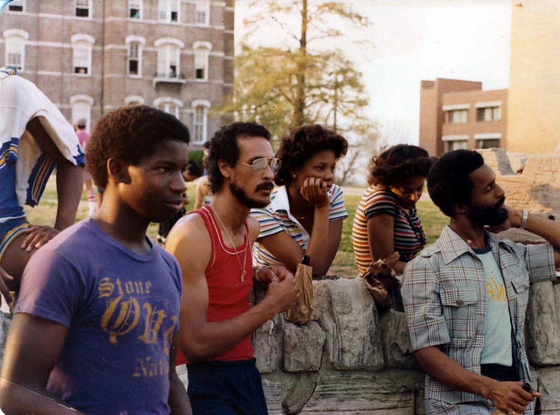 Tony, in a red tank top and glasses, with friends on his college campus